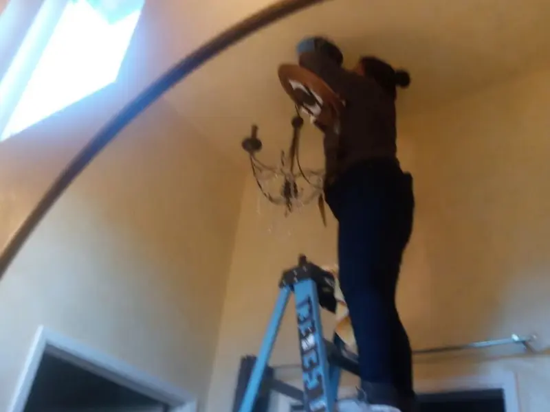 Electrician installing a chandelier in a Placitas residence
